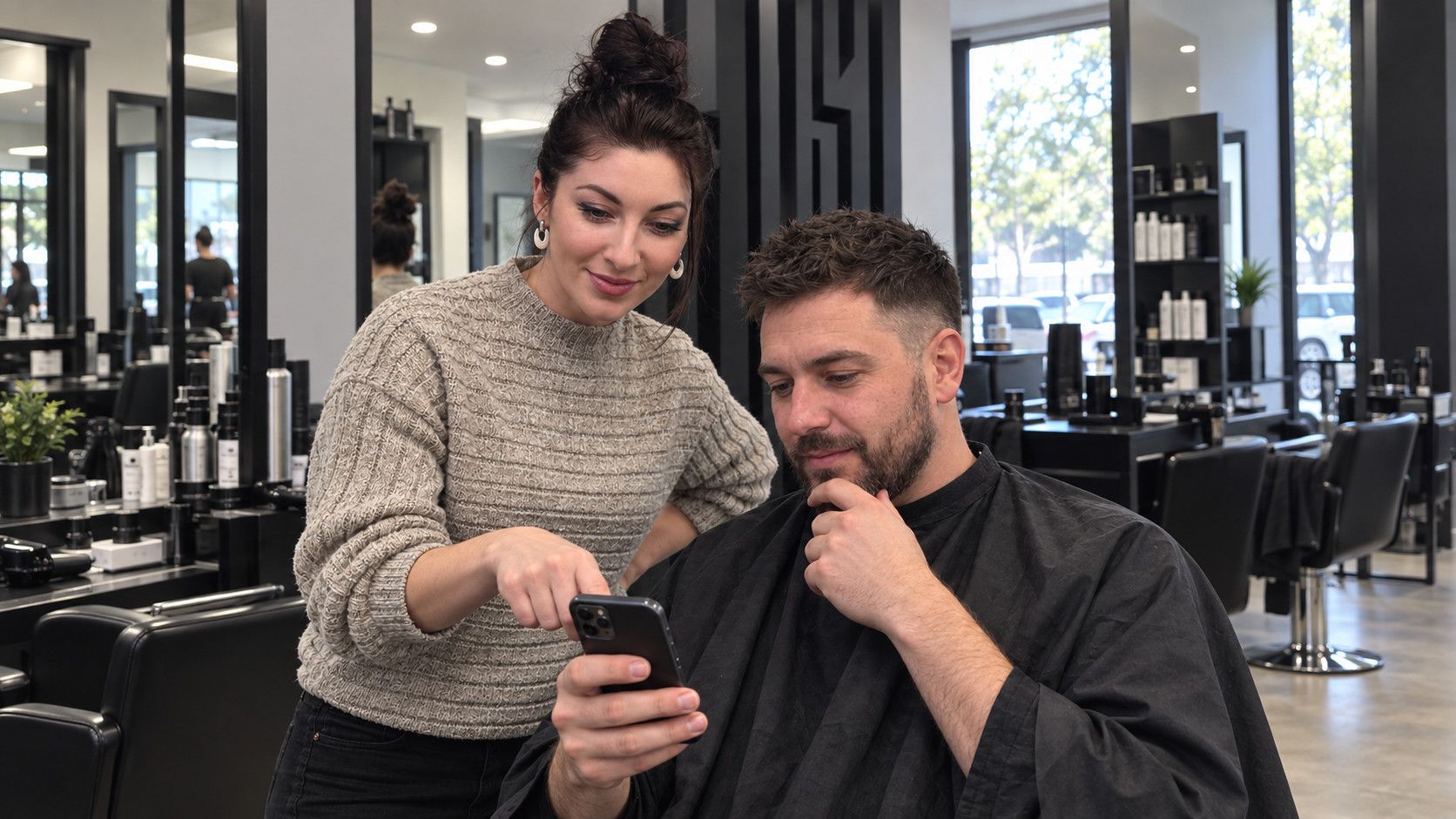 Barber discusses a haircut reference photo with a client