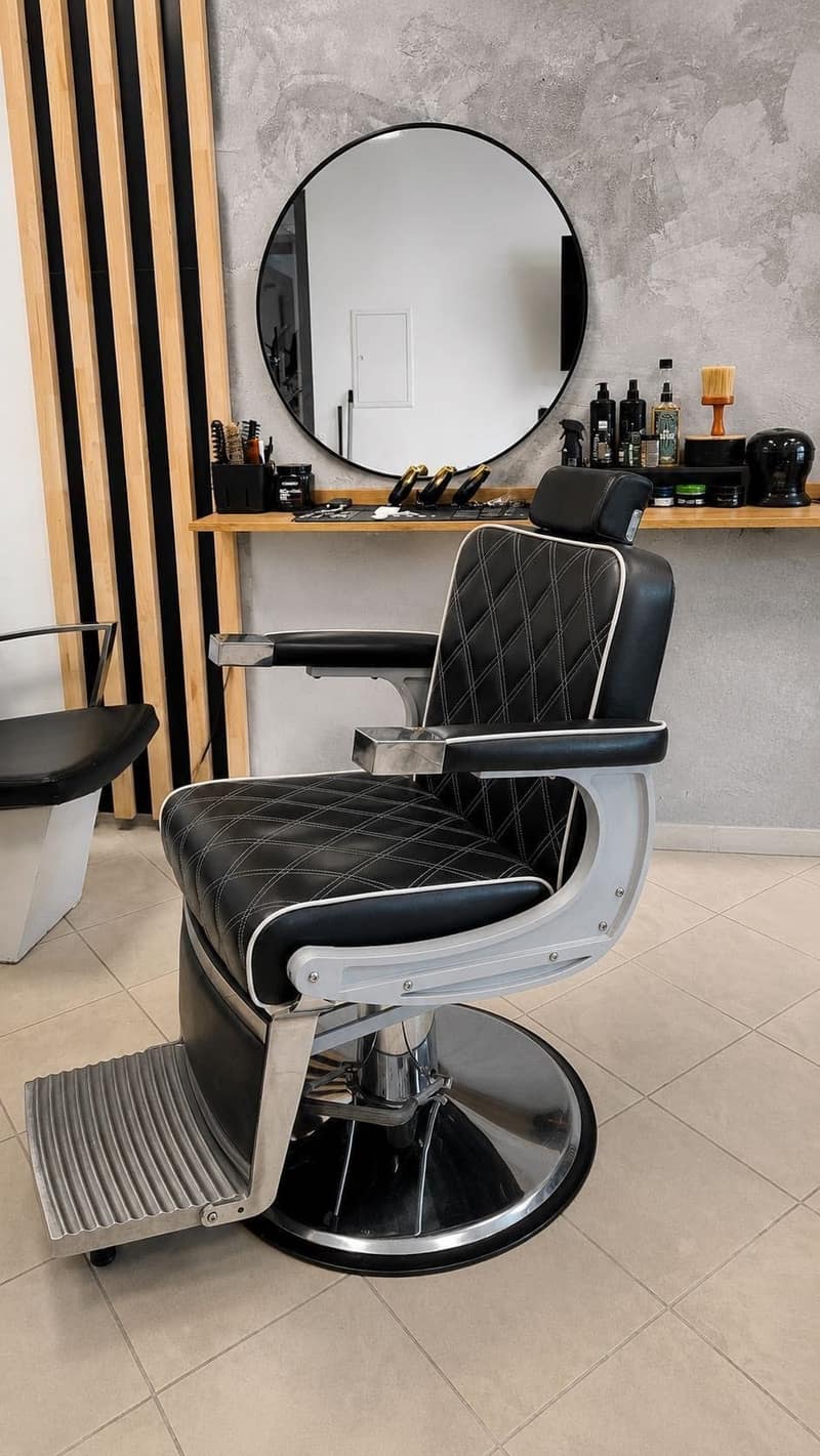 Czarny profesjonalny fotel barberski przed okrągłym lustrem w salonie ALIA Barber