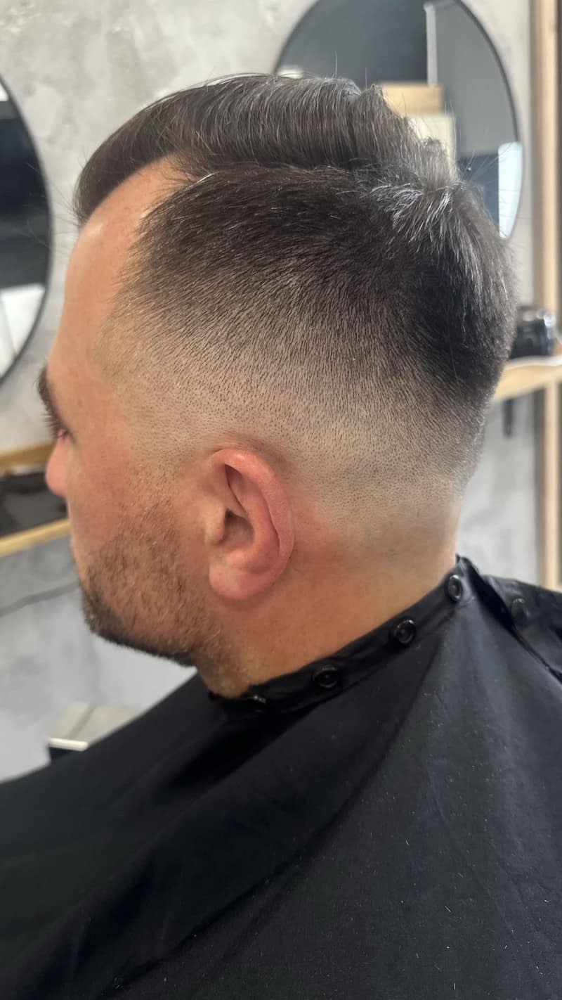 Męskie strzyżenie z uniesioną górą w stylu pompadour i płynnym fade po bokach