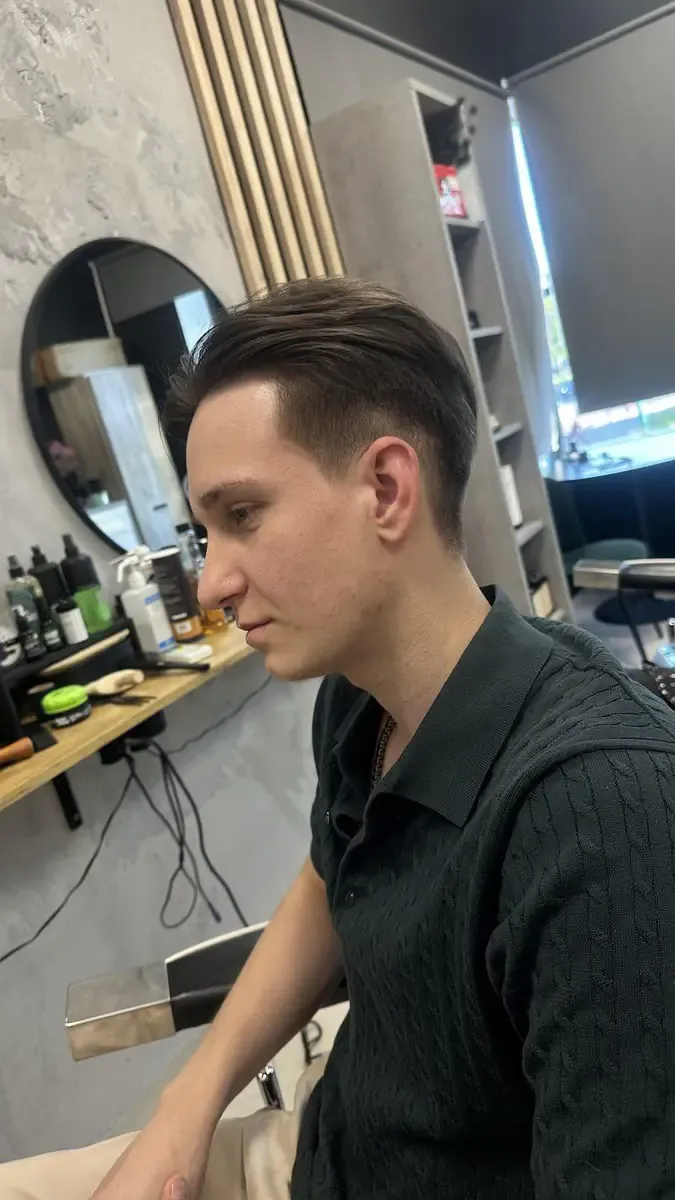 Męska fryzura slick back zaczesana do tyłu z krótszymi bokami i płynnym fade