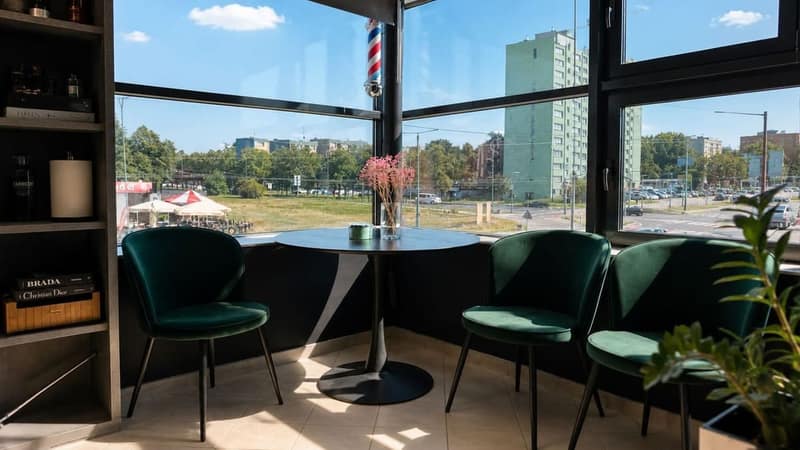 Strefa relaksu ALIA Barber Tychy z zielonymi fotelami i stolikiem przy dużych oknach